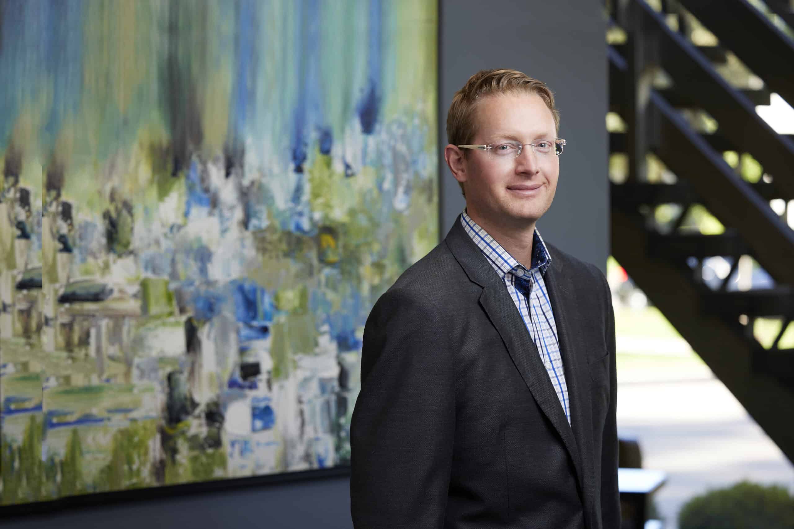 An image of Ben Goes CPA, an associate at Ford Keast LLP in standing in the lobby of the London Ontario office.