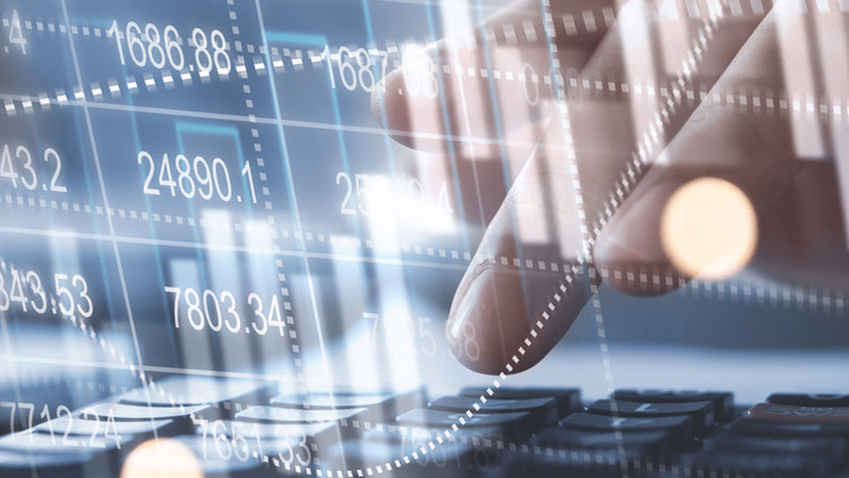 An abstract image of a person working on their computer and financial information projected above the keyboard.
