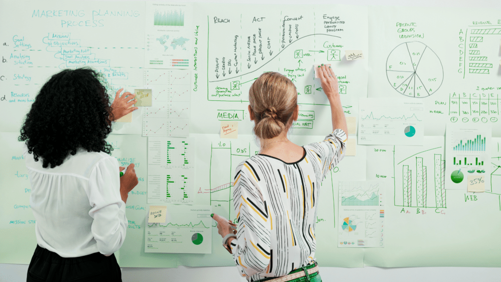 An image of two small business owners reviewing their marketing strategy on a whiteboard at their London Ontario office.