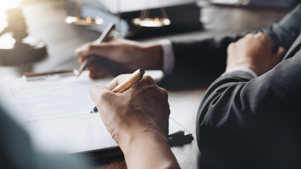 An image of two employees reviewing and signing new contracts in their office.