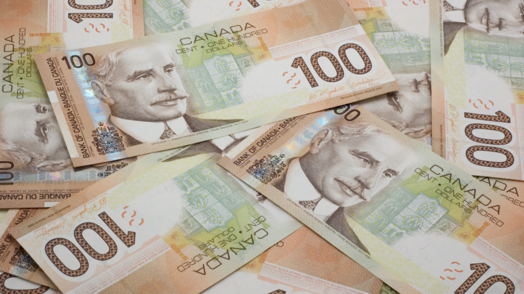 An image of a many $100 Canadian bills laid out on a table